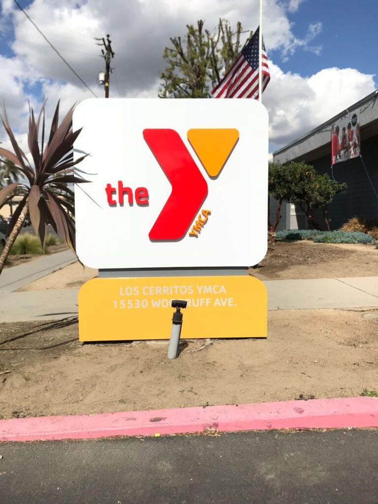 A white, yellow, and red monument sign advertising the YMCA