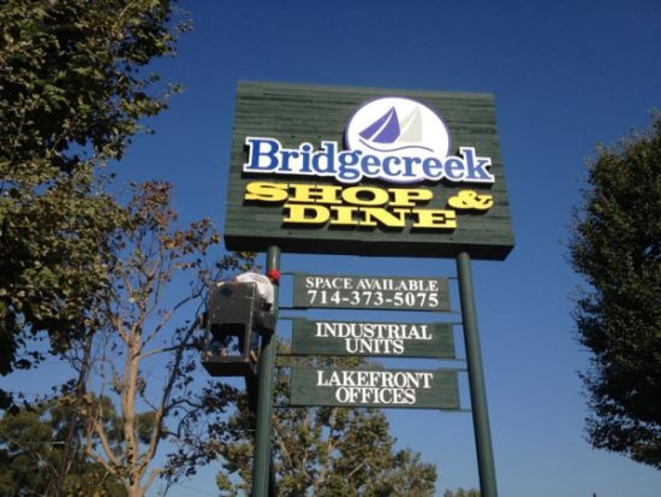 a twin-pole mount pylon sign advertising Bridgecreek Shop & Dine.