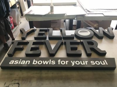 a foam lettering sign being constructed for a restaurant called Yellow Fever