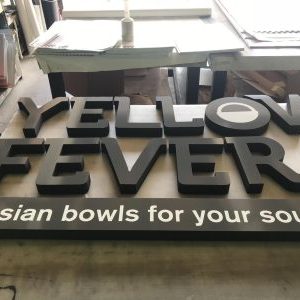 a foam lettering sign being constructed for a restaurant called Yellow Fever